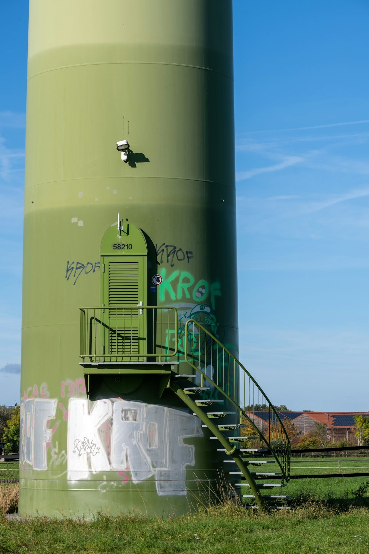 Green wind turbine tower with graffiti and stairs