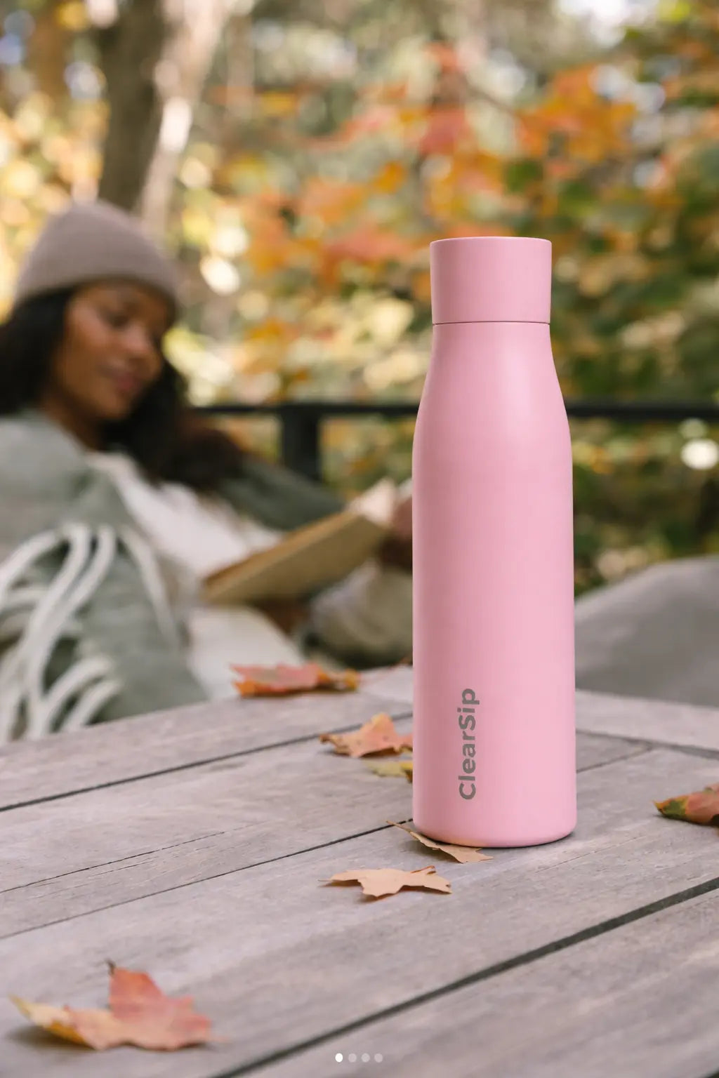 Herbruikbare roze waterfles van ClearSip op houten tafel in herfstomgeving, duurzame en gezonde drinkoplossing